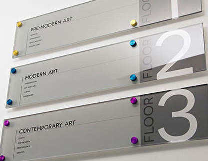 Multi-tiered wall mounted directional signage using custom metal standoffs